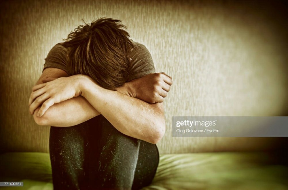 A sad man sitting on a bed