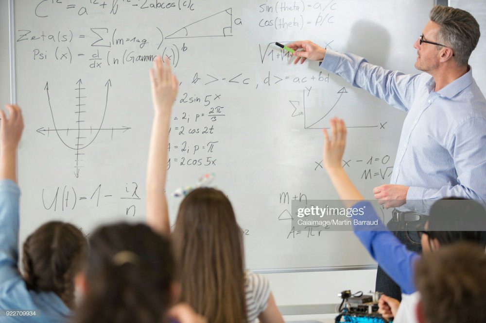 Male teacher teaching Physics lesson at whiteboard in classroom