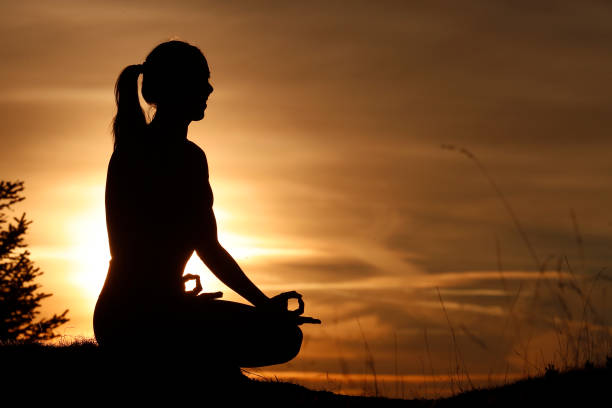 A silhouette of girl meditating on height
