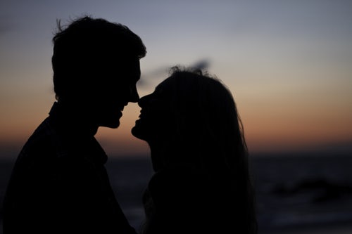 The silhouette of a girl and a boy who are just about to kiss